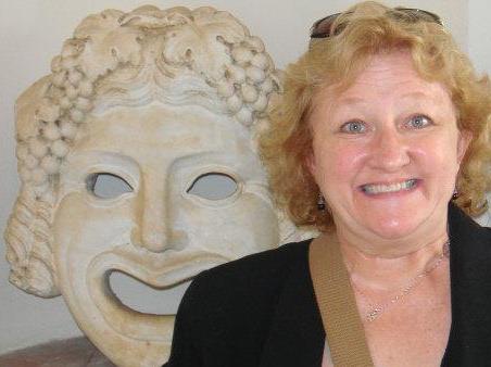 Rebecca Luttrell Briley smiling next to a classical sculpture mask